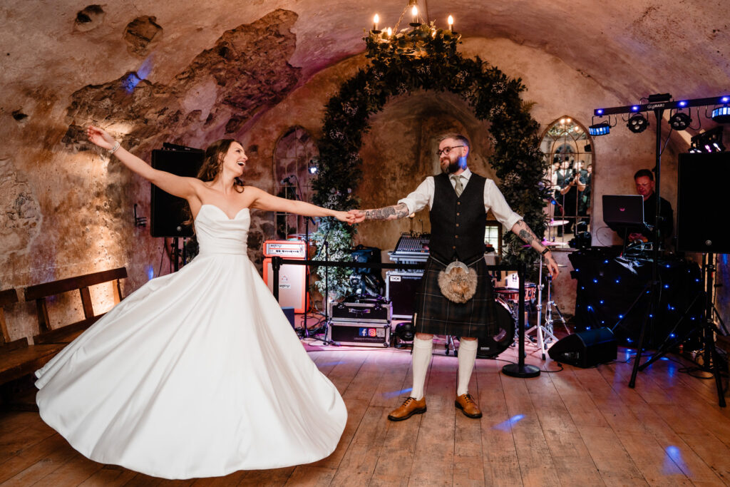 Bride and groom dance together at their Scottish castle wedding reception with live music and floral decorations