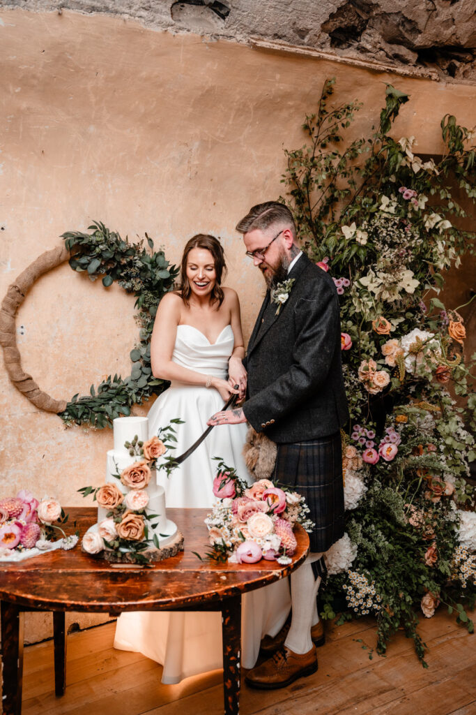 Bride and groom cut their wedding cake surrounded by lush floral decorations