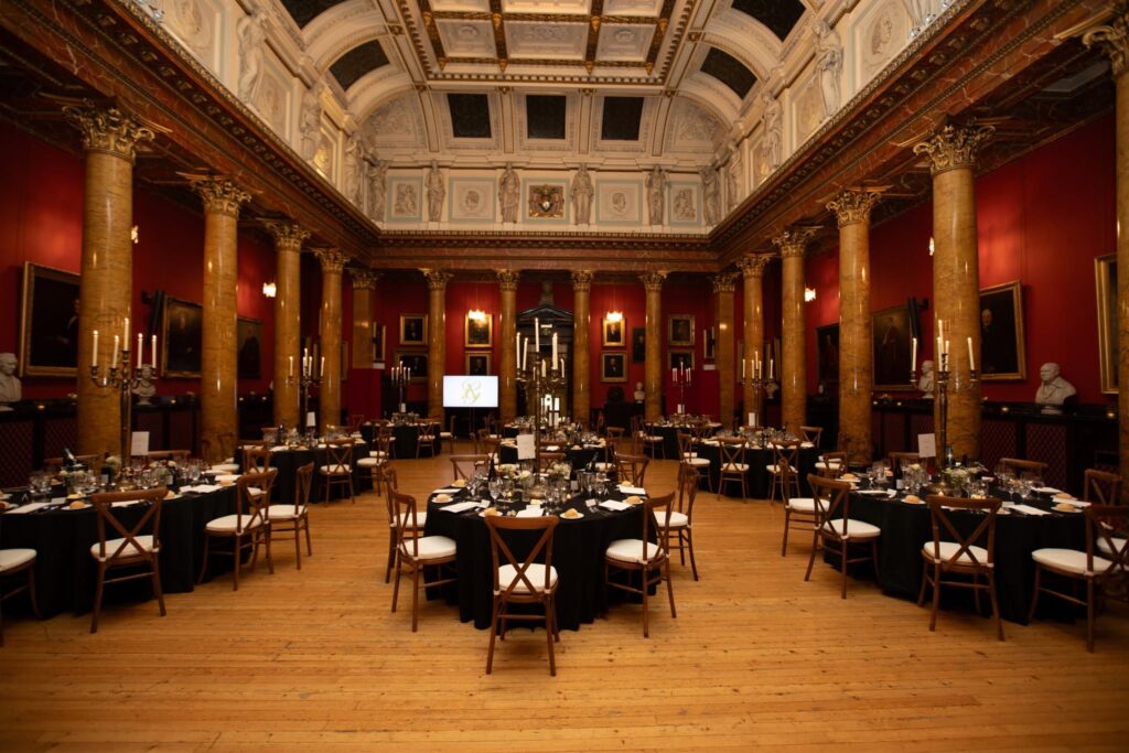 The Great Hall at the Royal College of Physicians of Edinburgh beautifully prepared for Alan and Gillian’s wedding reception, with elegant round tables, candlelit centrepieces, and grand historic architecture creating a timeless setting.